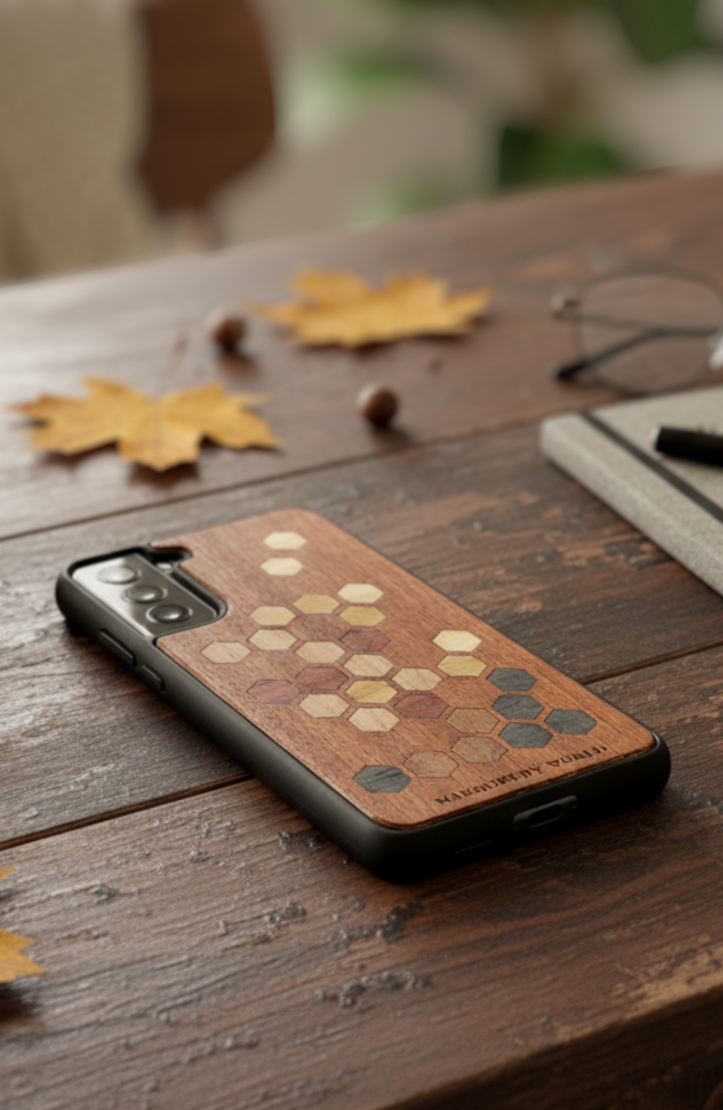 Phone case with honeycomb pattern on a wooden surface with leaves and glasses.